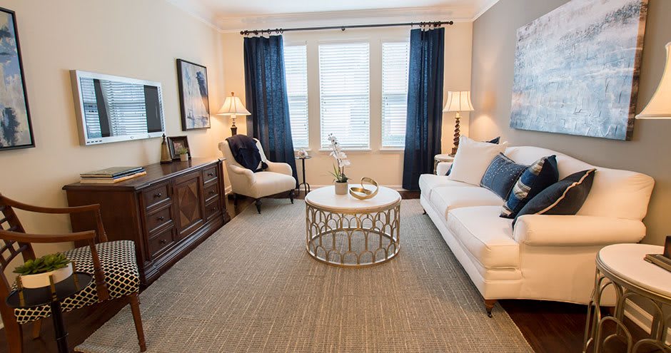 A cozy and well-decorated living room with a sofa, armchair, coffee table, and elegant lighting.