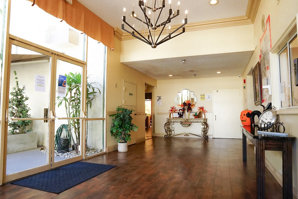 A well-lit lobby area featuring a wooden floor, elegant chandelier, and decorative elements.