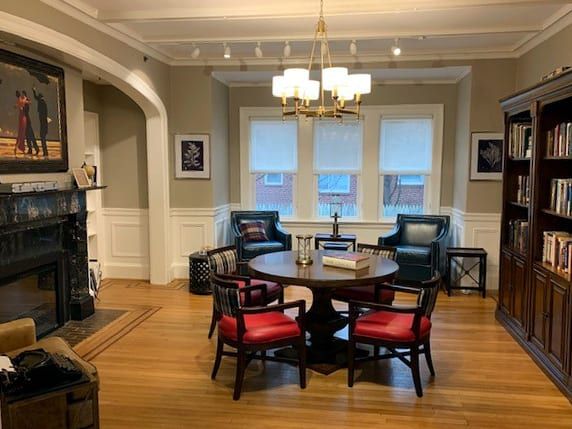 A cozy living room with a round table, red and black chairs, and a chandelier.