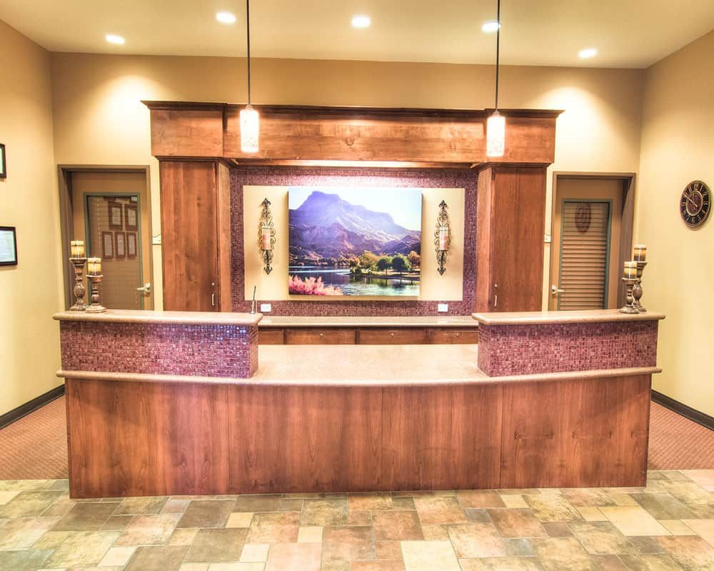 A well-lit reception desk with wood paneling and a scenic artwork on the wall.