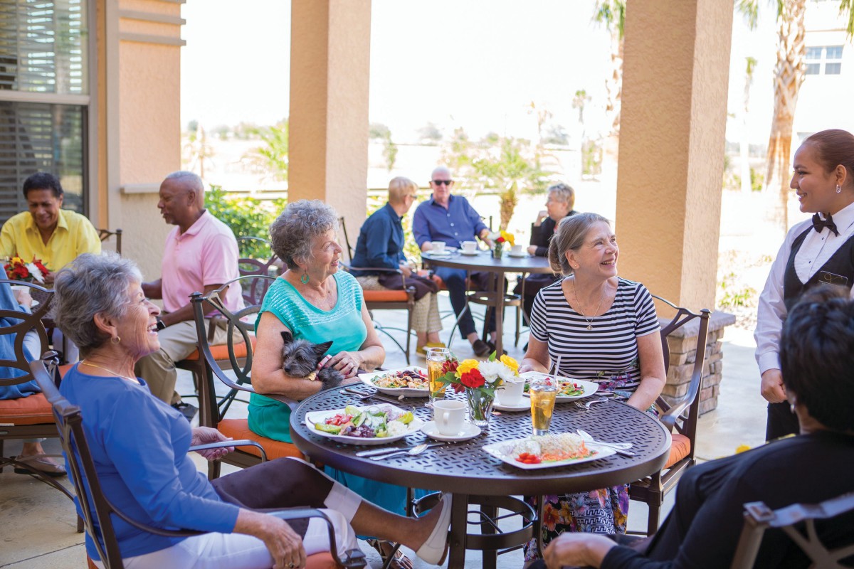A group of seniors enjoying a meal and conversation at an outdoor restaurant.