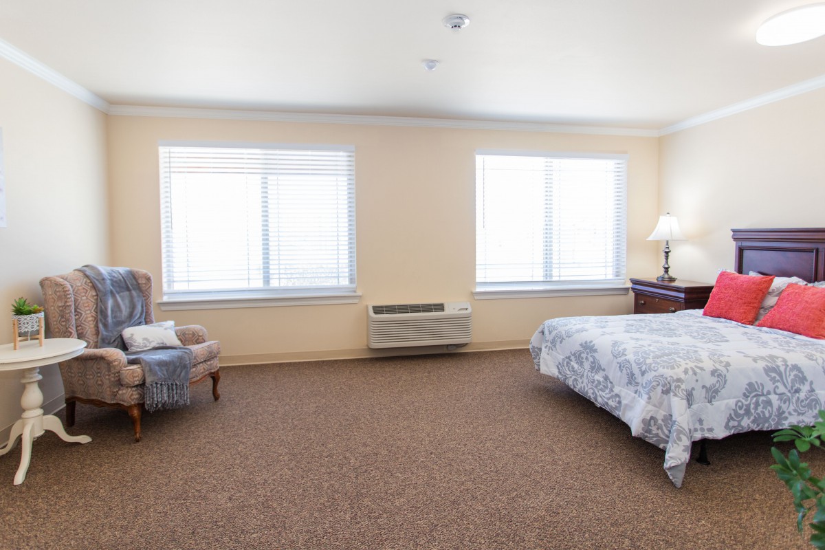 A spacious bedroom with a large bed, two windows, and comfortable seating.