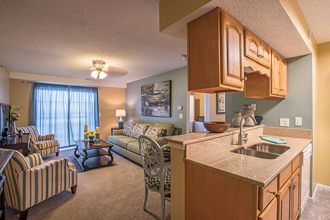 A cozy apartment interior featuring a living room and kitchen area with modern furniture and warm lighting.