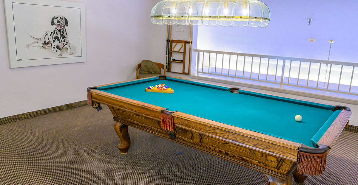 A pool table with billiard balls arranged, located in a cozy game room.