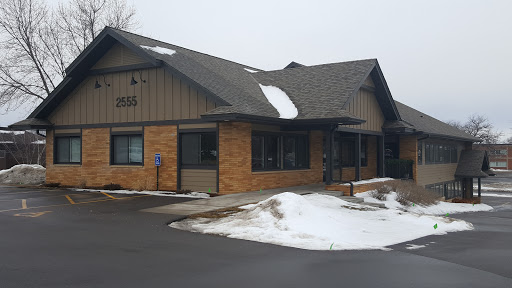 A modern building with a combination of brick and siding, partially covered in snow.