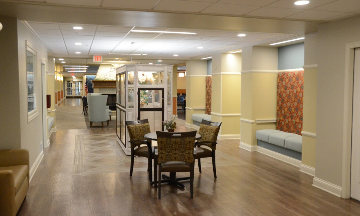 A well-lit lobby area with a table and chairs, leading to a hallway.