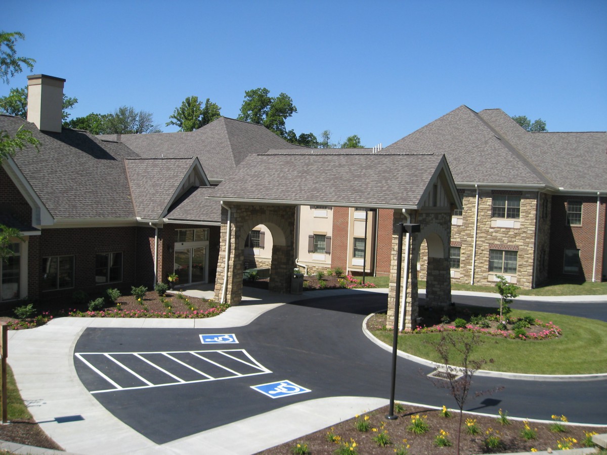 A residential building with a parking lot and landscaped surroundings.