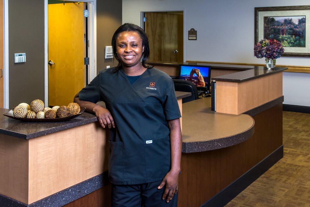 A woman standing near a reception desk in an office environment.