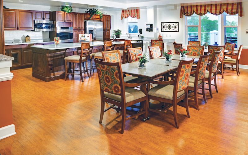 A cozy dining area with patterned chairs and a kitchen in the background.