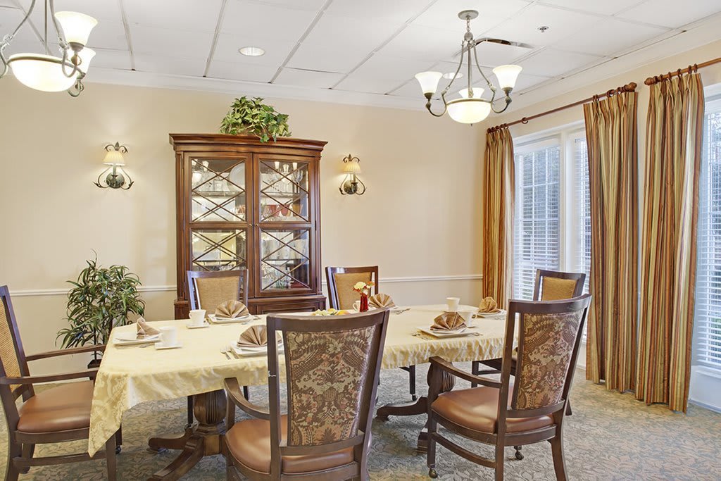 An elegant dining room featuring a large table set with chairs and a decorative chandelier.