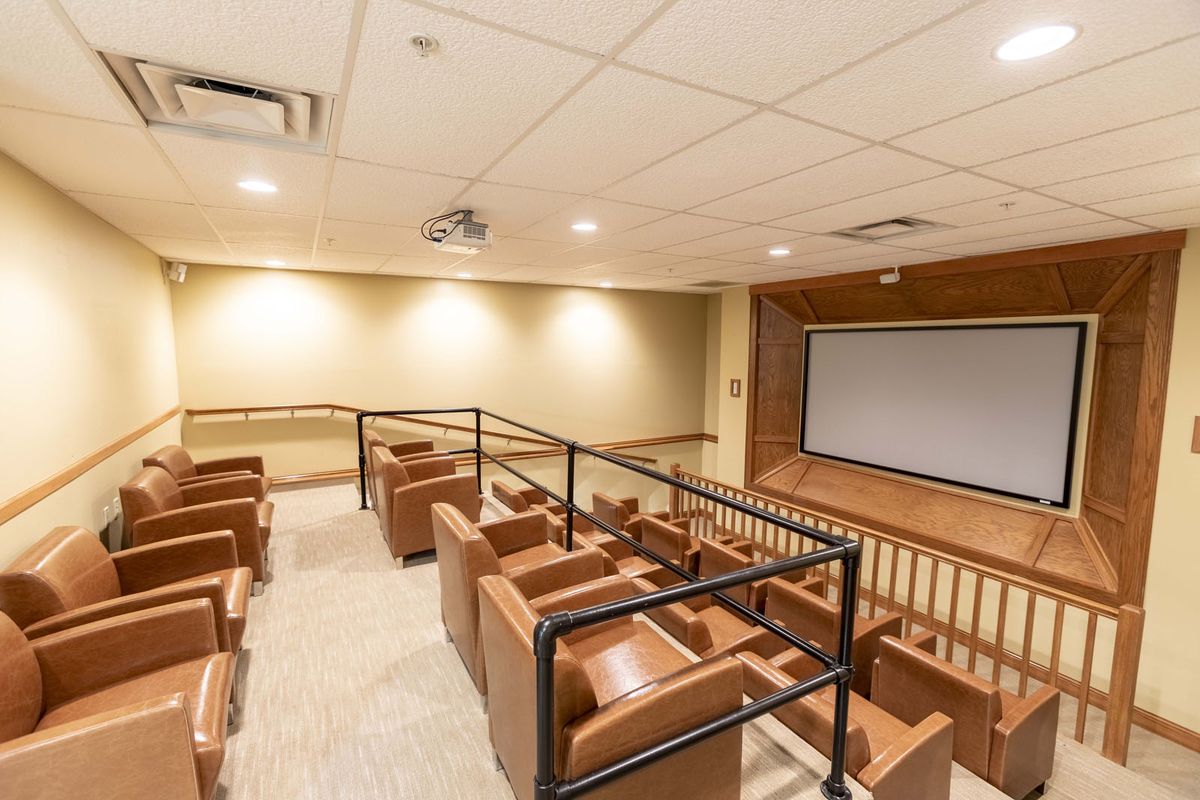 A small indoor home theater with tiered seating and a large projection screen.