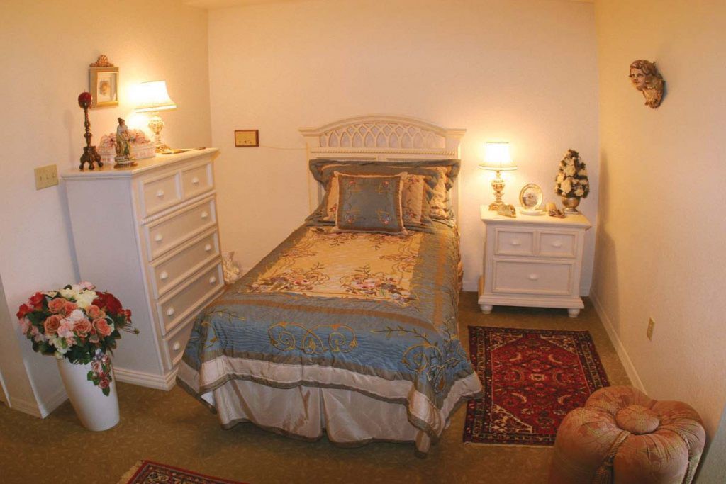 A cozy bedroom with a bed, nightstand, dresser, and decorative lamps.