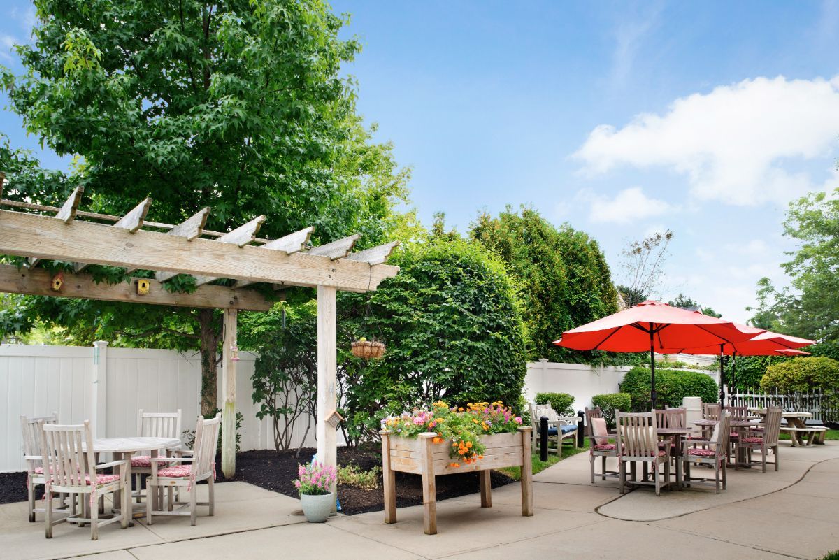 A beautiful outdoor patio featuring a pergola, seating area, and lush greenery.