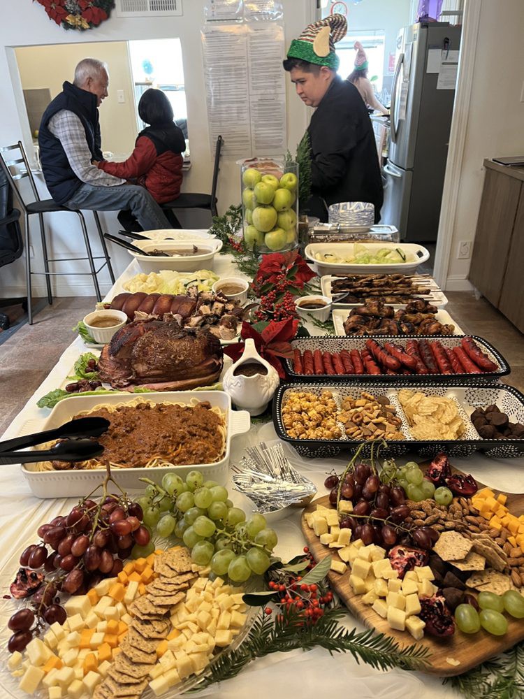 A buffet table filled with a variety of meats, fruits, and dishes at a gathering.