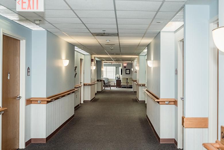 A well-lit corridor with handrails and light fixtures on the walls.