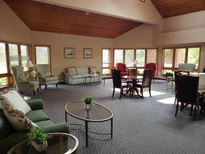 A spacious living room with sofas, chairs, and coffee tables, featuring large windows that let in natural light.
