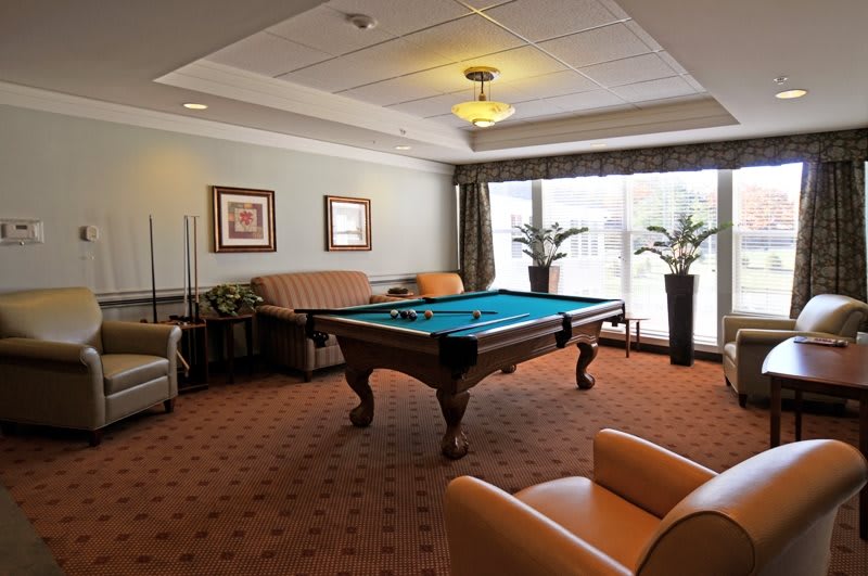 A cozy game room featuring a pool table surrounded by comfortable seating and decor.