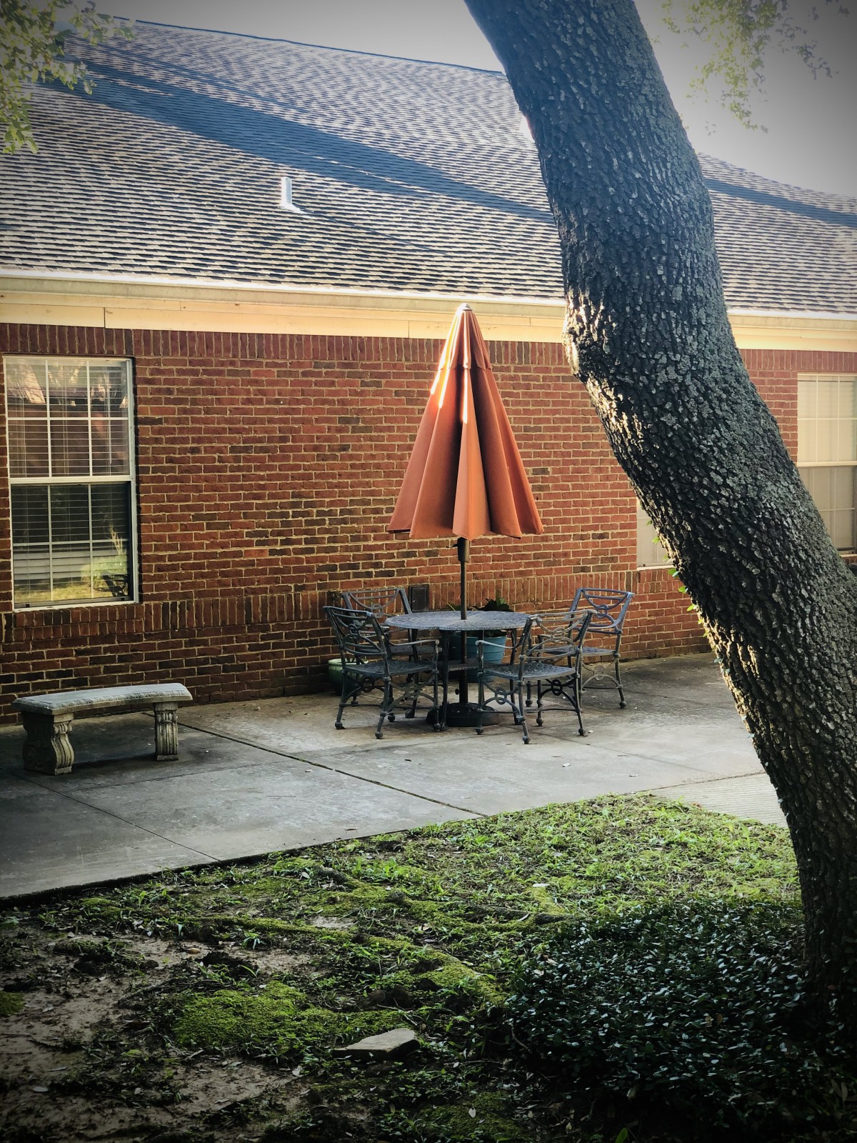 A cozy outdoor patio area with a table, chairs, and an umbrella next to a brick building.