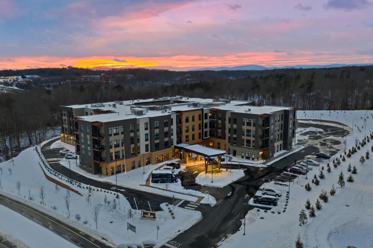 Aerial view of an apartment building surrounded by snow during sunset.