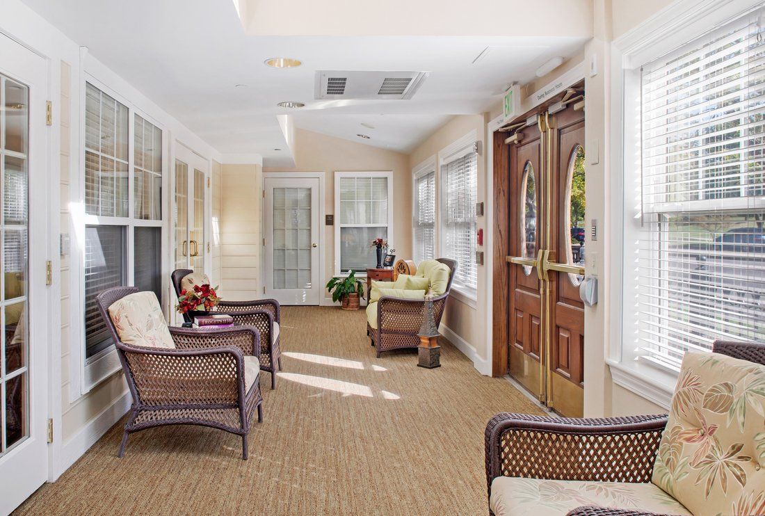 A cozy sunroom with wicker furniture and ample natural light streaming in through large windows.