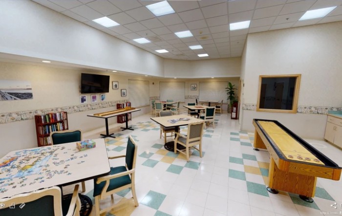 A spacious indoor dining area with tables and chairs, featuring a television on the wall.