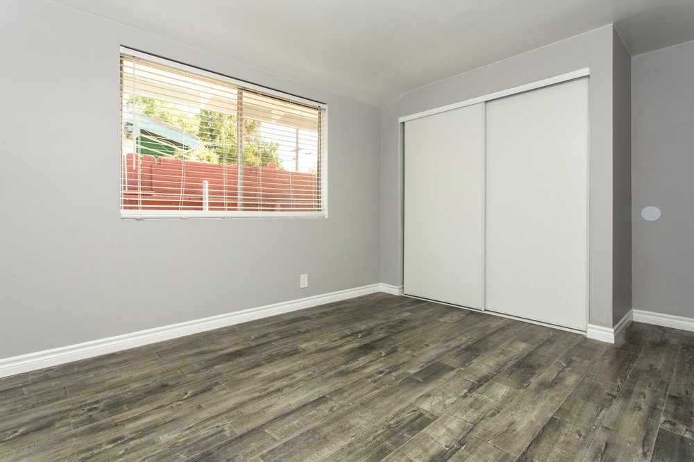 A simple, unfurnished room with laminate flooring and a window.