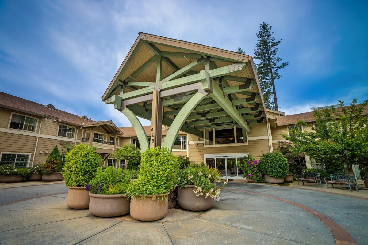 A modern building entrance with lush greenery and unique architectural design.
