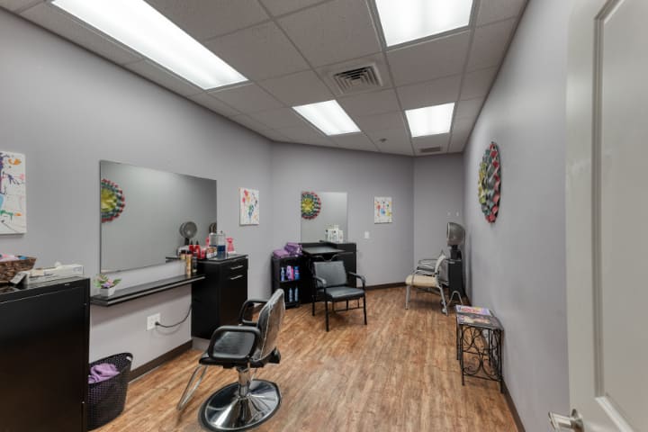A small salon interior with a hair cutting station, mirror, and chairs.