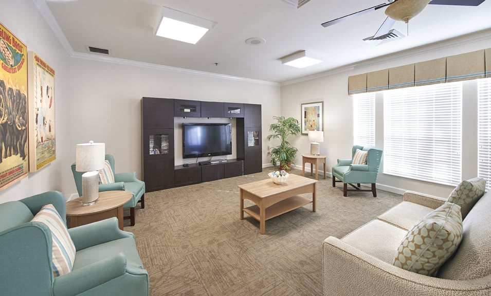 A modern living room with neutral tones, featuring a large television, comfortable seating, and stylish furnishings.