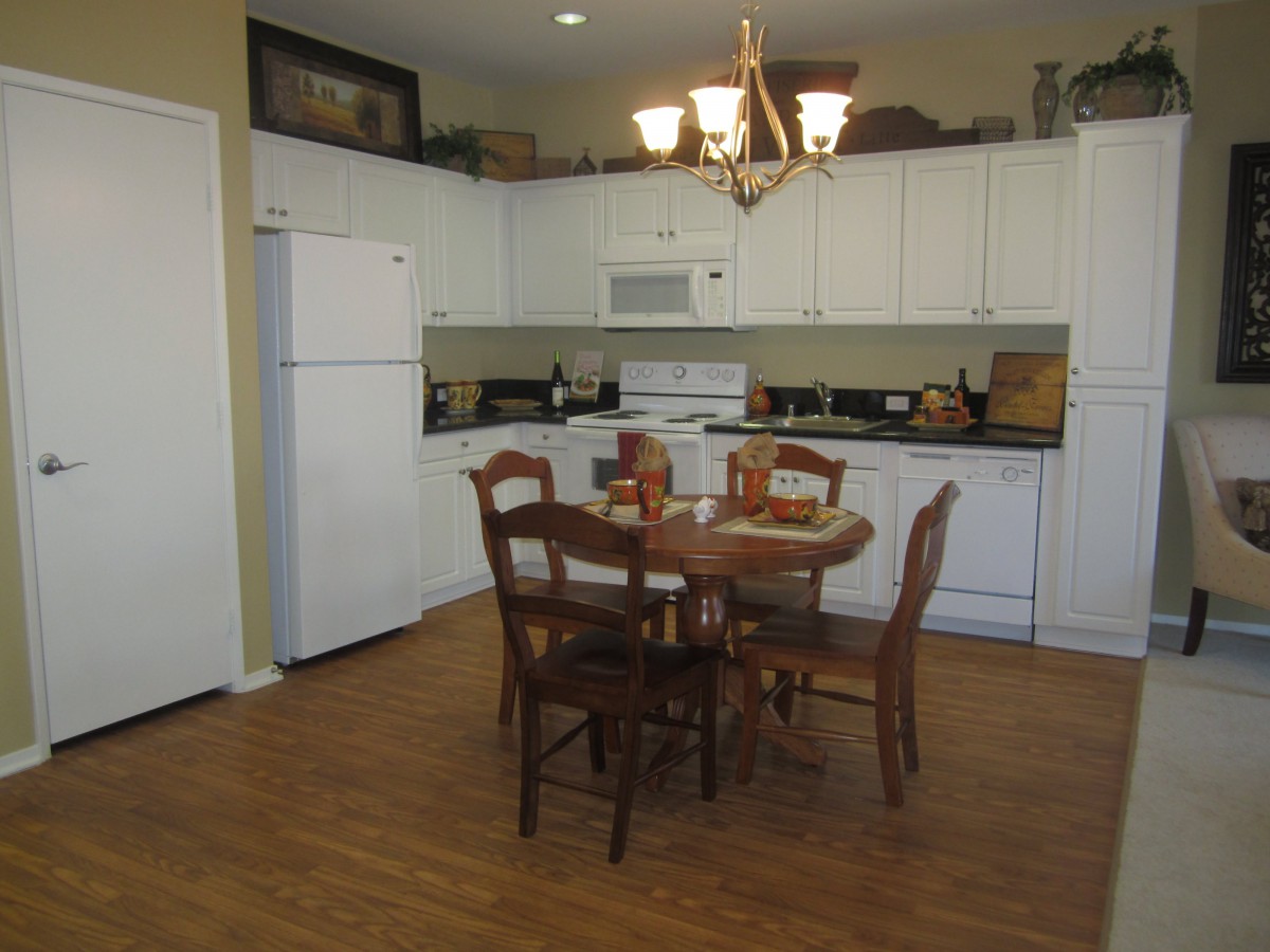 A cozy kitchen and dining area featuring white cabinets, a wooden dining table set, and a chandelier.