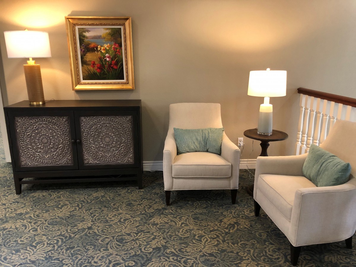 A cozy living room setting with two armchairs, a side table with a lamp, and a painting on the wall.