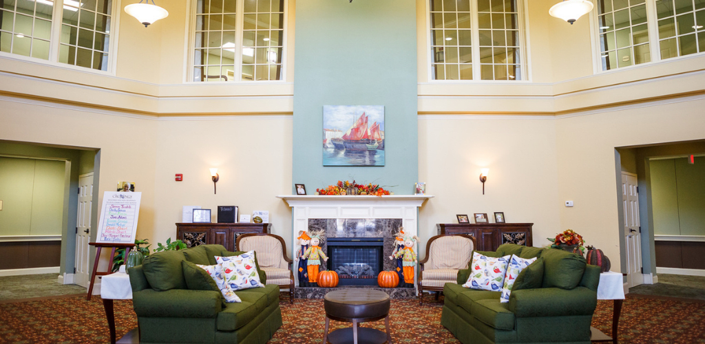A cozy living room with autumn-themed decor and a central fireplace.