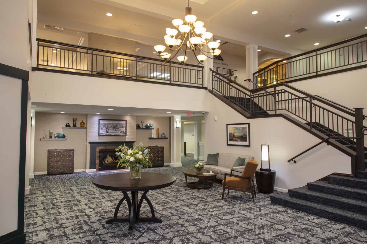 A spacious hotel lobby with a grand staircase and elegant chandelier.