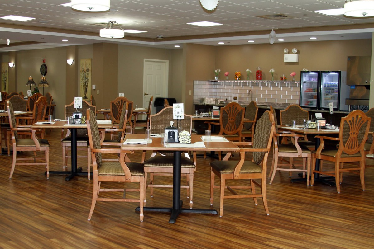 A spacious dining area with wooden tables and chairs, featuring warm lighting and a cozy atmosphere.
