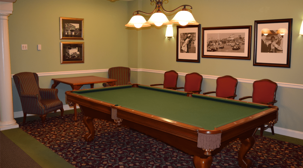 A cozy game room featuring a classic pool table, elegant lighting, and vintage wall art.