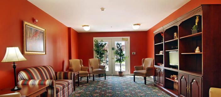A cozy waiting area with red walls, comfortable chairs, and natural light streaming through the glass doors.
