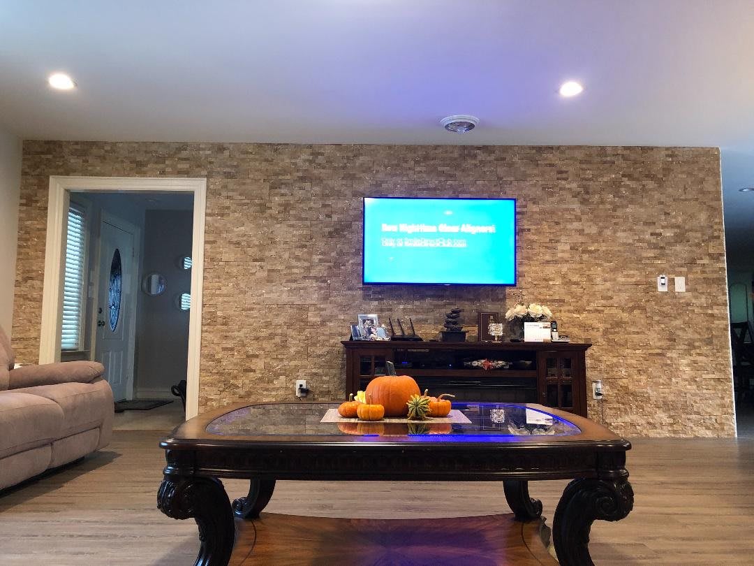 A cozy living room with a stylish stone accent wall, featuring a coffee table adorned with fruit decorations and a mounted TV.