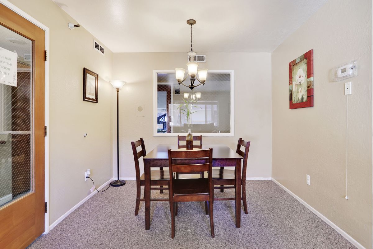 A cozy dining room with a wooden table and chairs, illuminated by a ceiling light fixture.