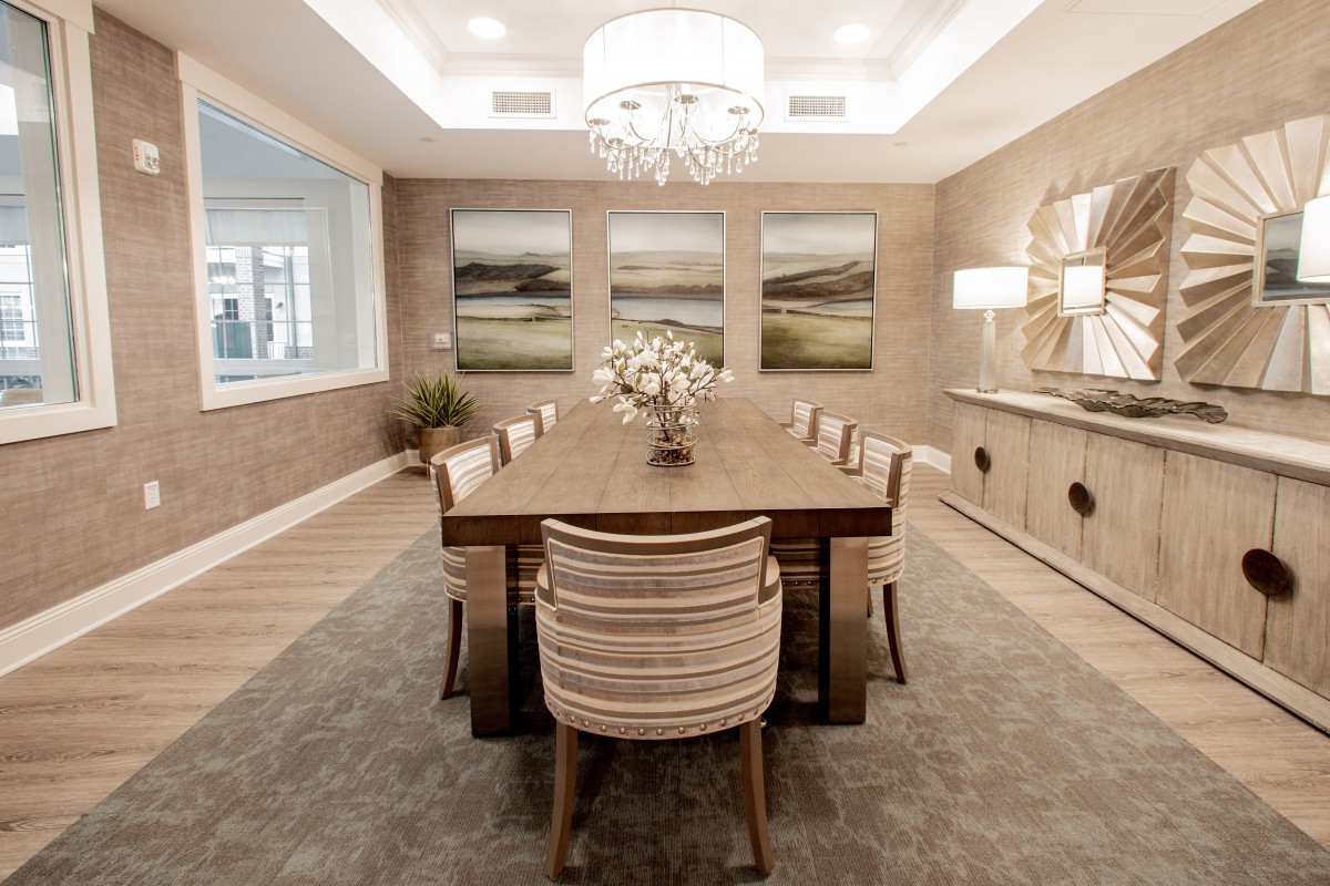 A modern dining room with a large wooden table, elegant chairs, and a chandelier overhead.