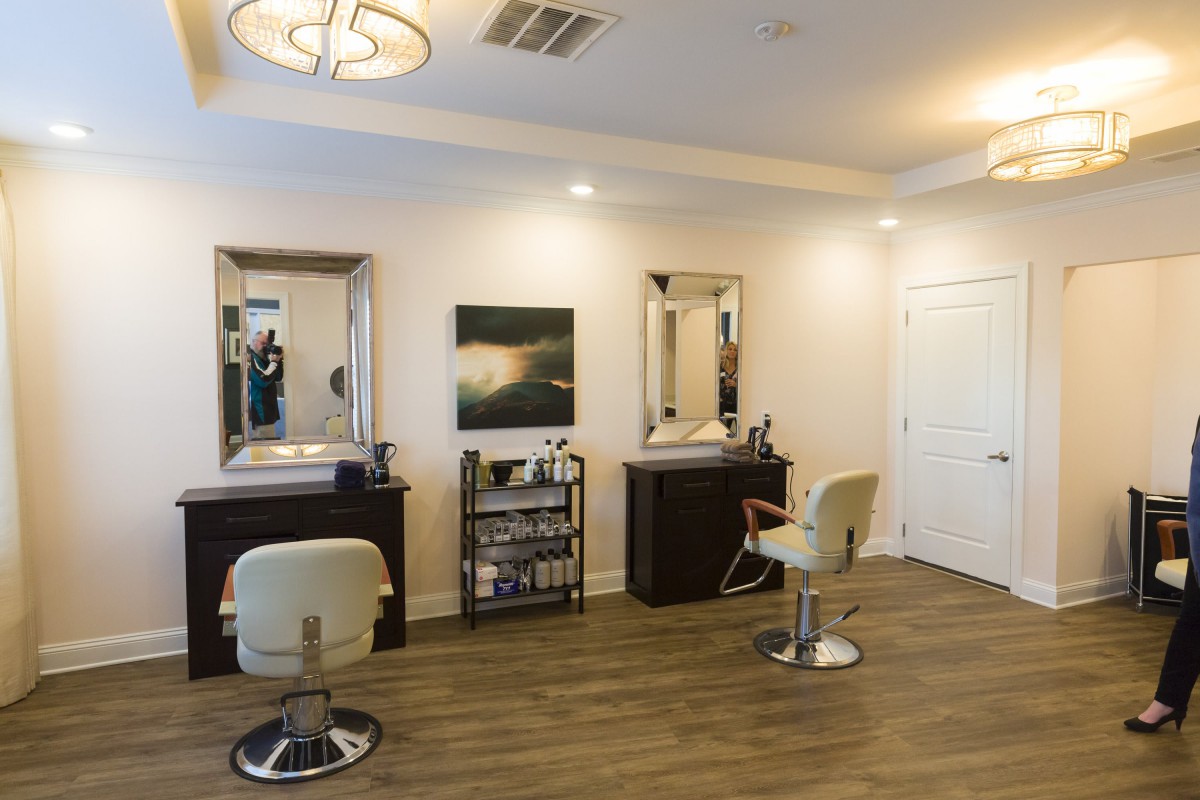 A modern hair salon interior with stylish chairs and mirrors, featuring a wooden floor and wall art.