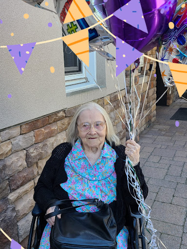A joyful elderly woman celebrates with colorful balloons.