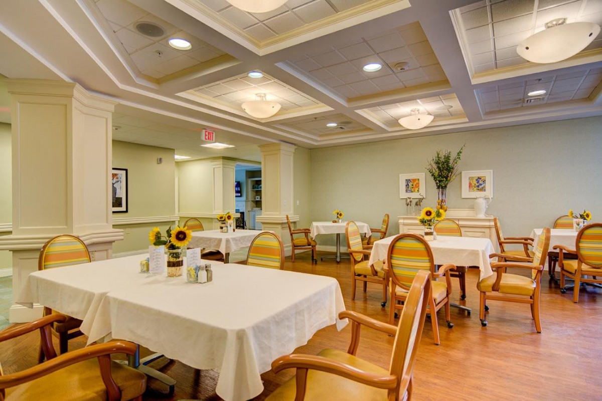 A neatly arranged dining room with tables and chairs, featuring elegant decor and warm lighting.