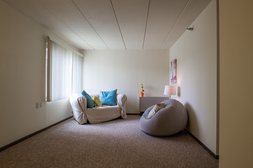 A minimalist living room featuring a cozy sofa with colorful cushions and a bean bag, bathed in natural light.