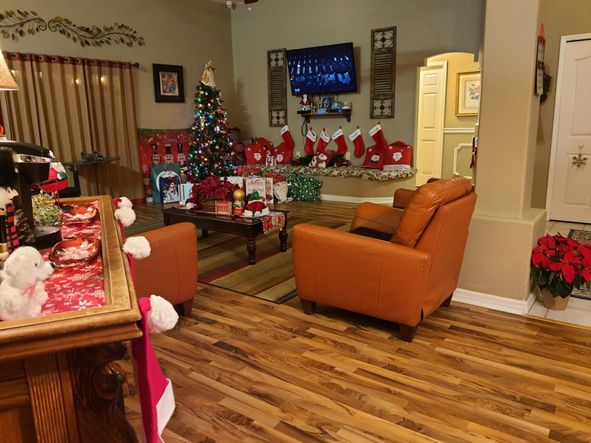 A cozy living room decorated for Christmas with a tree, presents, and stockings hung by the fireplace.