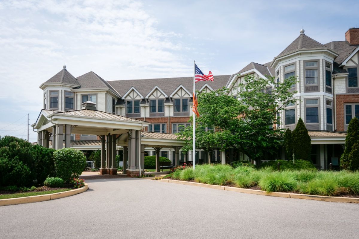 A large hotel building with a landscaped entrance and an American flag.