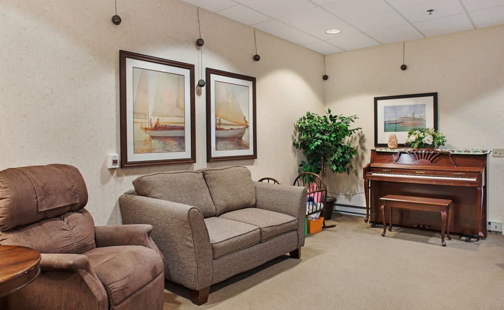 A cozy living room featuring a sofa, artwork on the walls, and a piano in the corner.