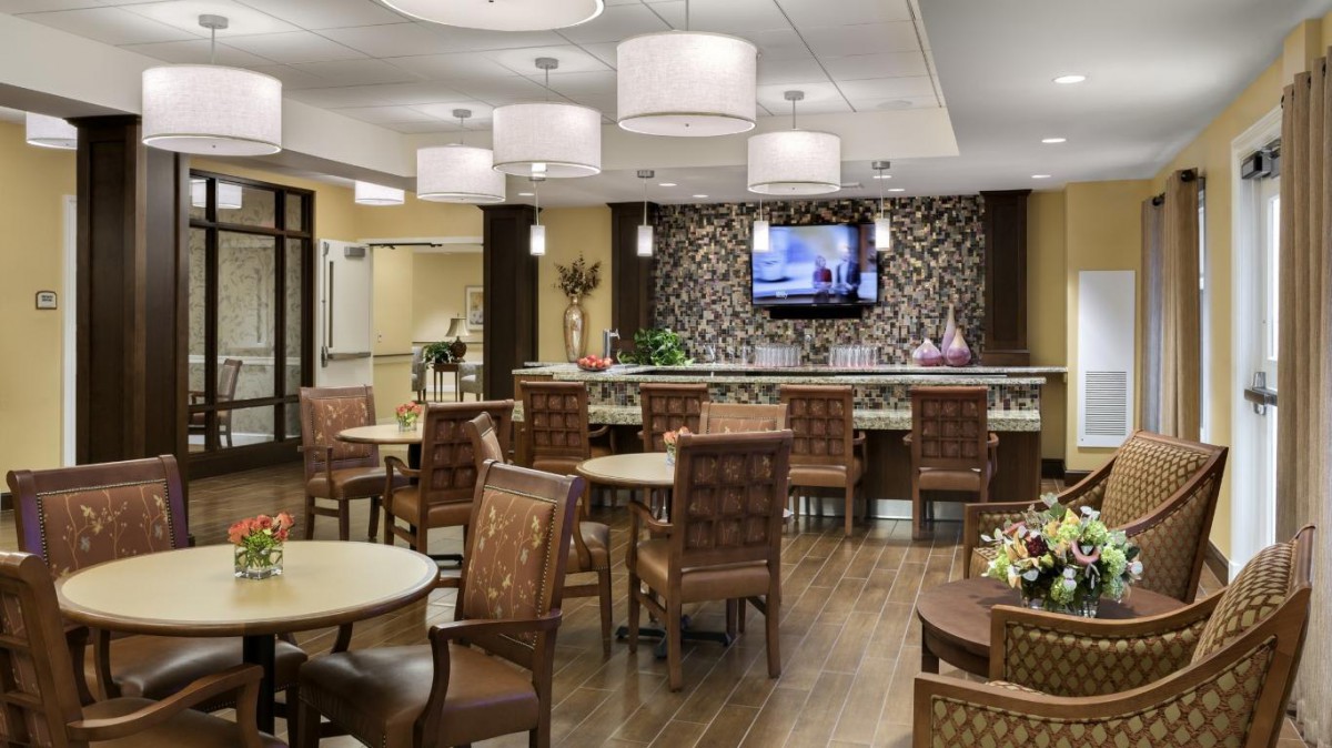 A modern dining area with stylish seating and a decorative wall, featuring soft lighting and a mounted television.