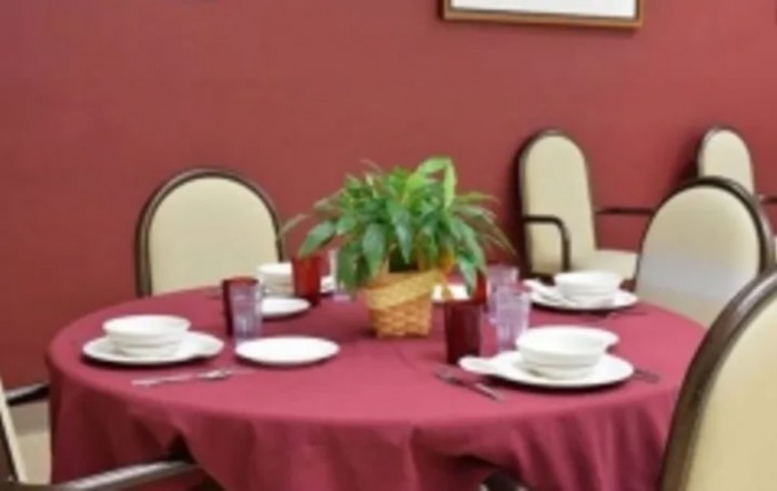A dining table set for a meal with a red tablecloth and a plant centerpiece.