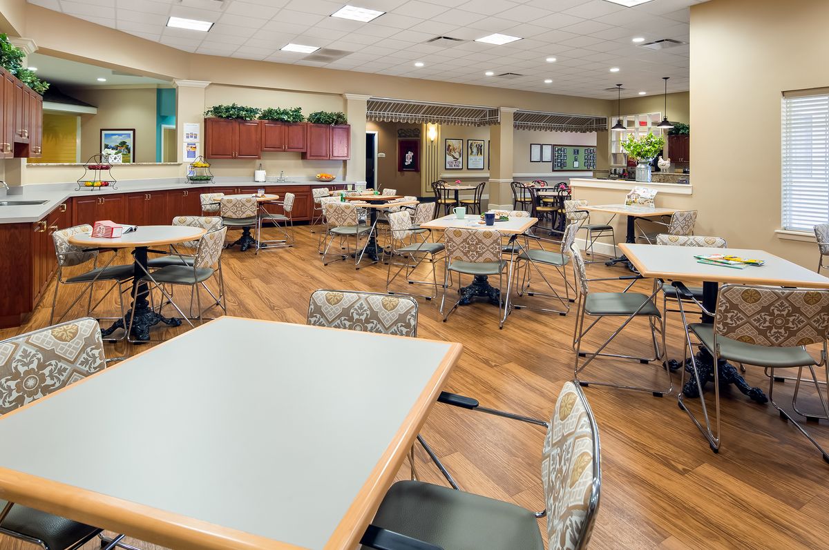 A modern dining area with tables and chairs, featuring wood flooring and a spacious layout.