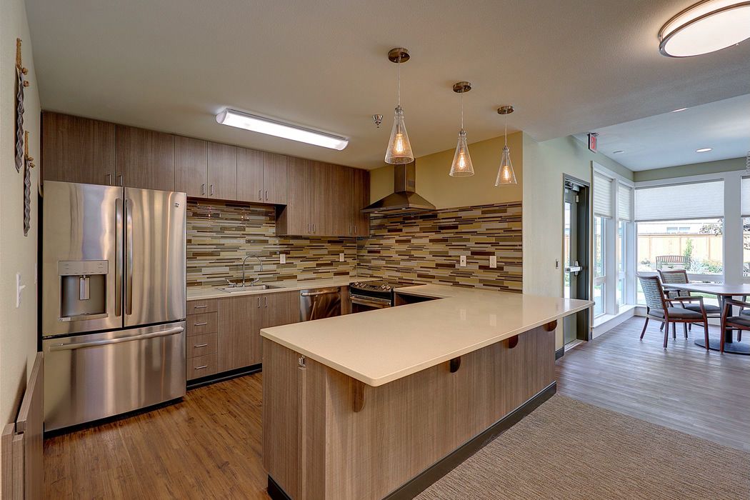 A modern kitchen with sleek wood cabinetry, a central island, and stainless steel appliances.